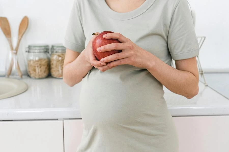 Gravid kvinna håller i rött äpple